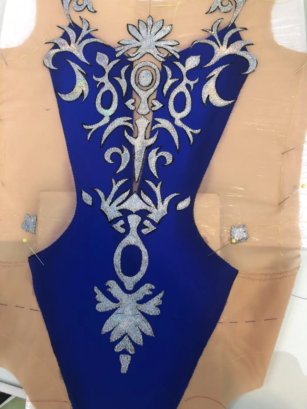 Royal blue competition leotard with silver scrollwork embroidery, in progress on a dress form.