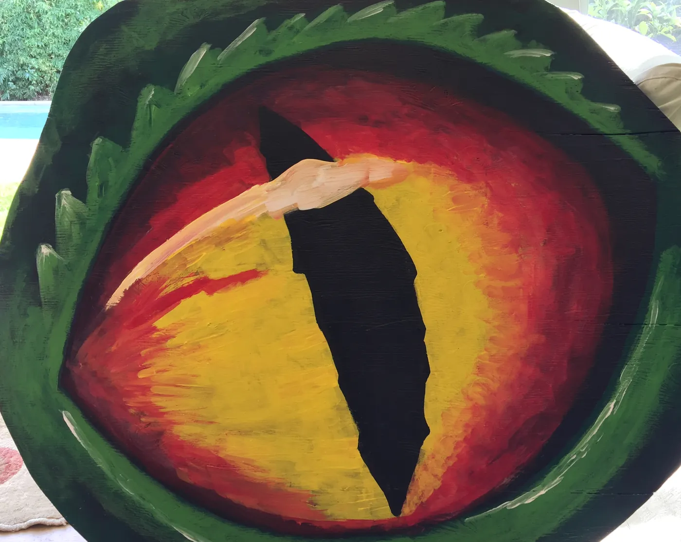 Painting of a reptilian eye in red and amber, ringed by deep green scales.