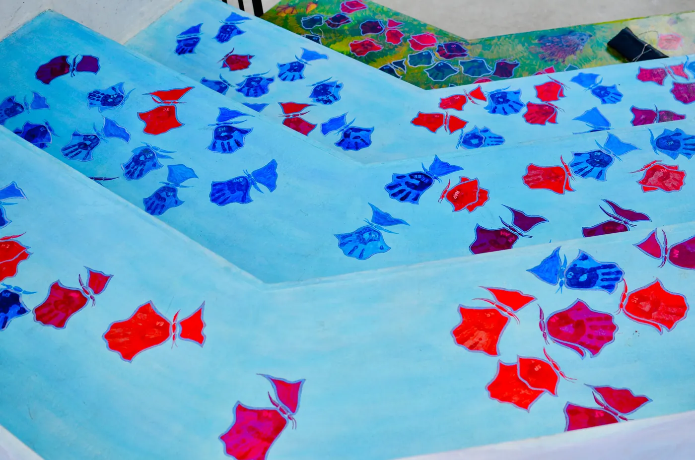 Mural of red and blue fish shoaling across pale blue steps.