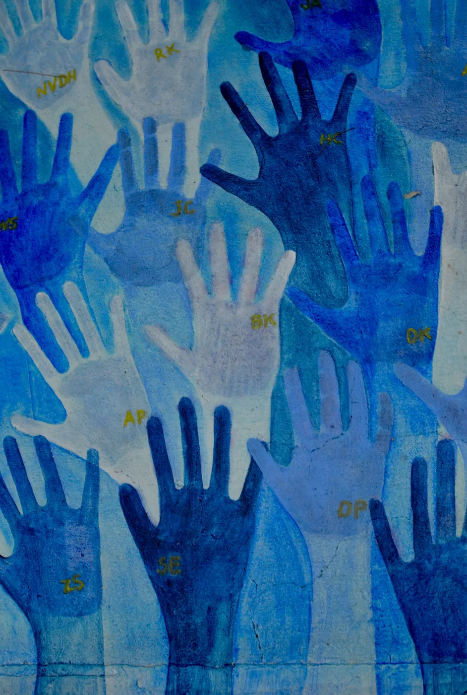 Mural of layered blue handprints, each signed with initials.
